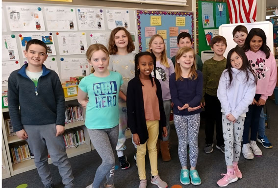 Third grade students standing in a group, smiling