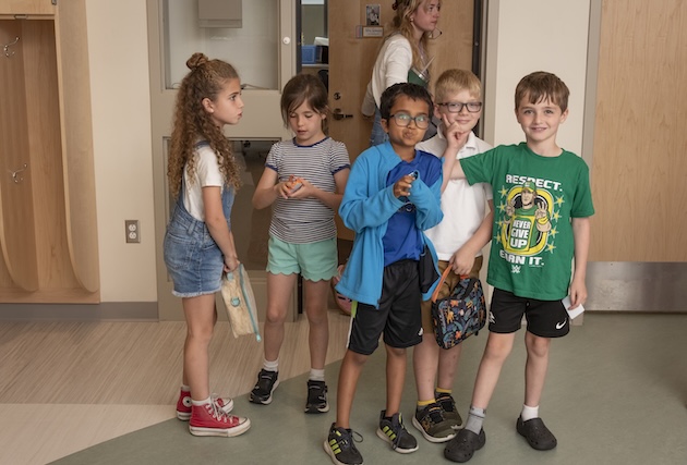 Five students are standing in the hallway.