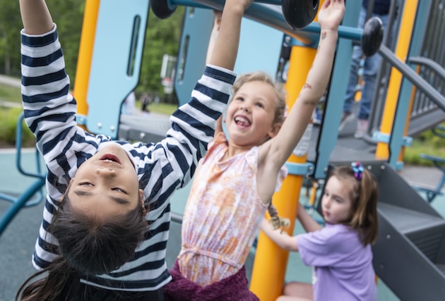 Two girls navigate the monkey bars at recess.