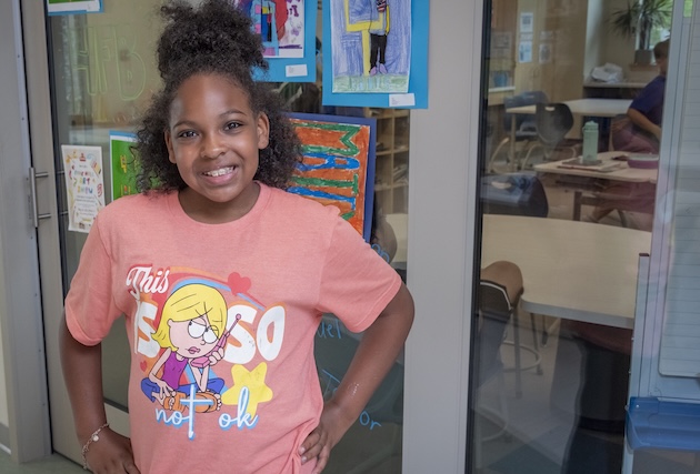 A young girl poses in the hallway.