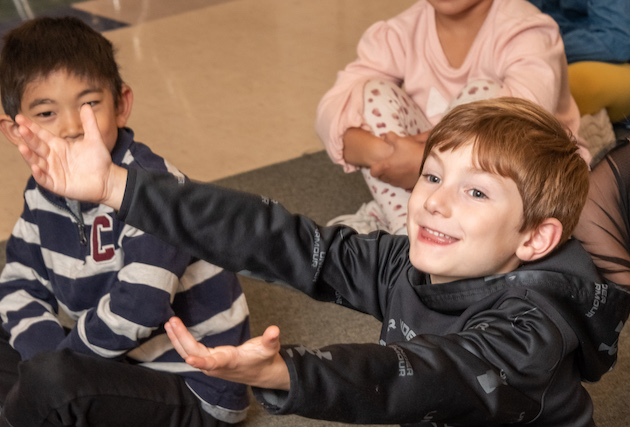 A student sitting on the floor with arms outstretched