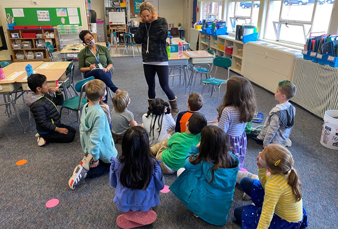 Students sitting on the rug listening to the Discovery Museum staff member