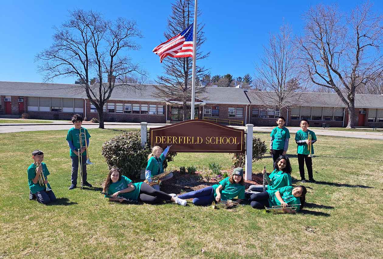Students surround the Deerfield School sign holding their instruments