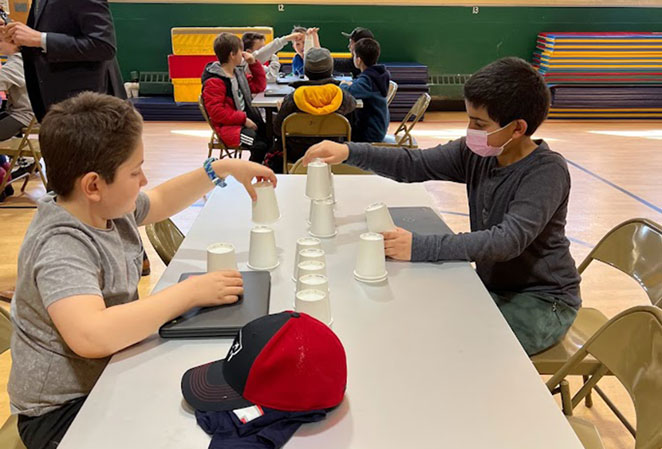 Students sitting at a table stacking cups