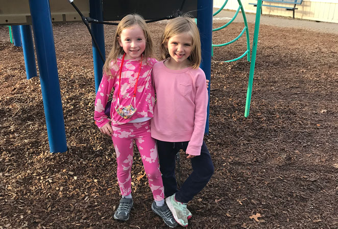 Two girls standing in front of playground equipment