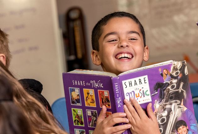 Student at Downey holding a book and smiling
