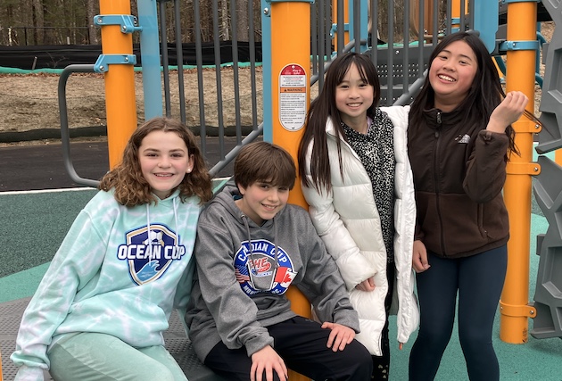Four fifth graders looking at the camera while on the playground.