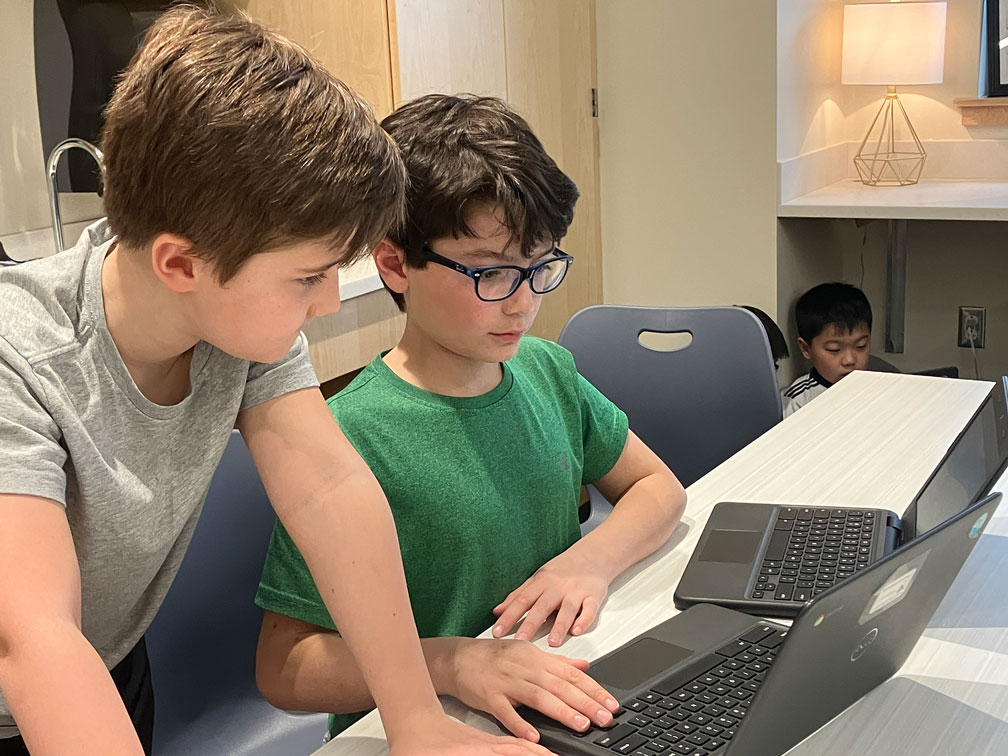 Two boys looking at a Chromebook.